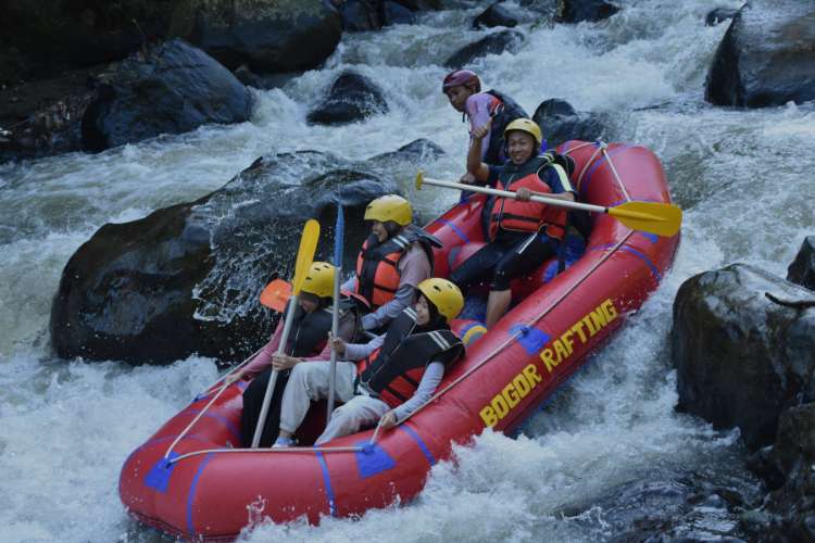 Peserta rafting keluarga meliuk di antara bebatuan Sungai Cisadane Bogor dengan perahu karet
