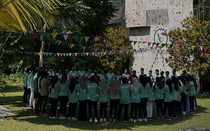 Aktivitas outbound teambuilding peserta perusahaan di lapangan terbuka samping fasilitas wall climbing ikonik Via Renata Puncak